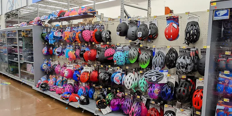 Cykelhjälmar i butikshylla i olika färger och storlekar