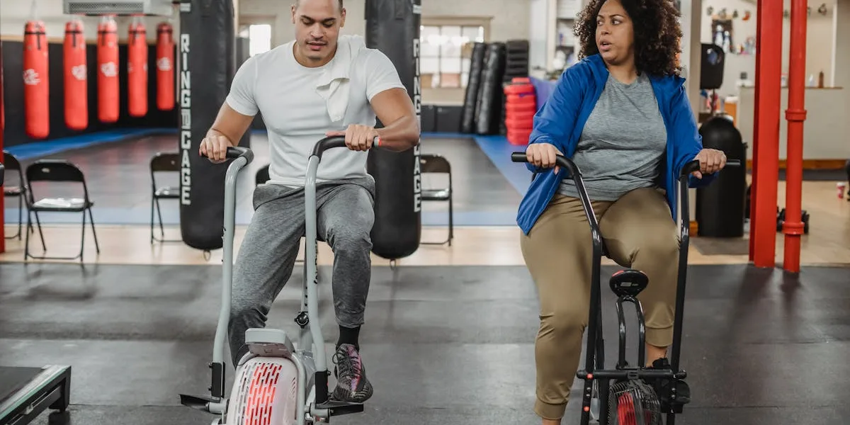 Två personer tränar på motionscyklar i gym