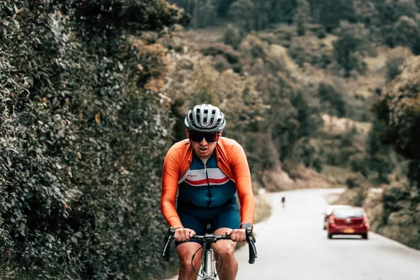 Cyklist i cykelkläder klättrar uppför backe