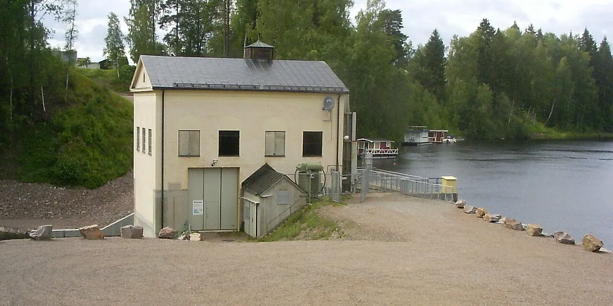 Gammalt vattenkraftverk vid älv omgivet av blandskog