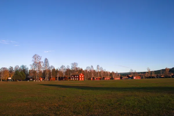Värmländsk gårdsmiljö med röda stugor i kvällsljus
