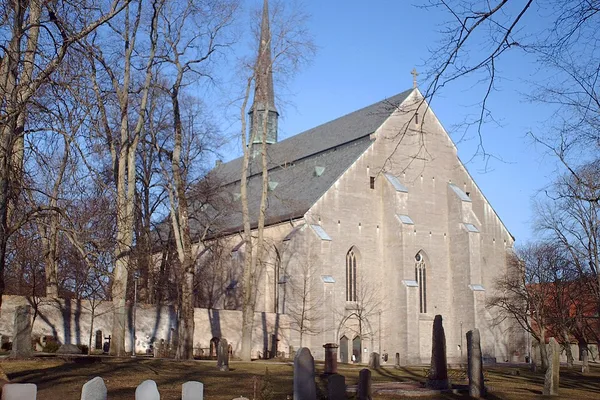 Vadstena klosterkyrka i gotisk stil med gravstenar och vinterträd
